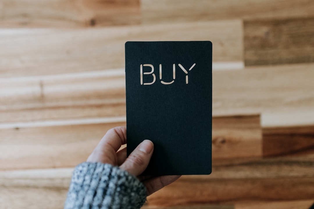Acheter ou construire une maison au Maroc a person holding a black book with the word buy written on it